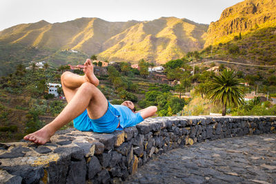 Mid adult man lying on rock against mountain