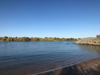 Scenic view of lake against clear blue sky