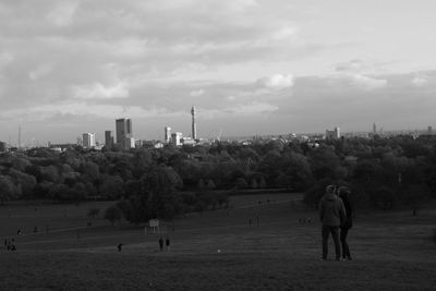 People on landscape against sky in city