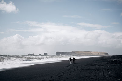 People walking on beach against sky