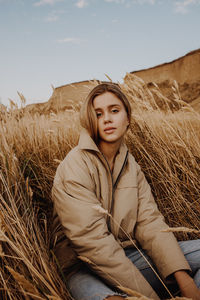 Portrait of beautiful young woman on field against sky