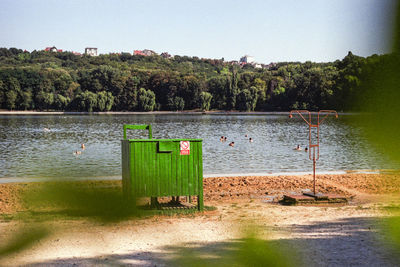 Deck chairs by lake against sky