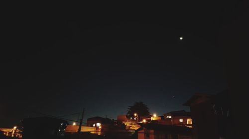 Low angle view of illuminated houses against sky at night