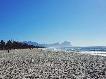 Scenic view of beach against clear blue sky