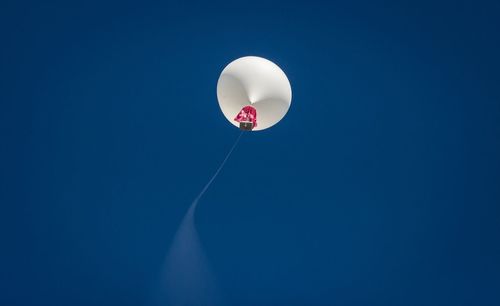 Low angle view of balloons against clear blue sky