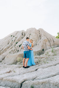 Couple standing on rock against mountain