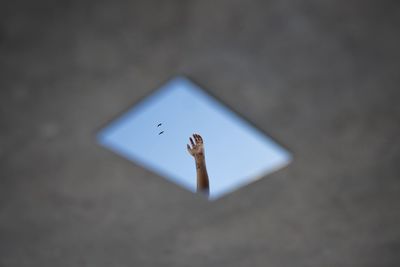 Low angle view of cropped hand against sky