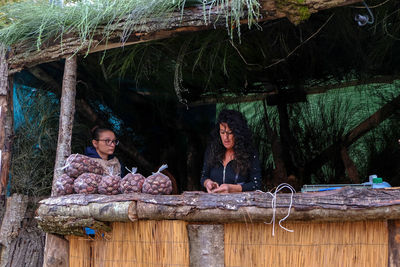 Portrait of people sitting by tree against plants