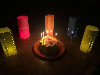 Close-up of illuminated candles on table in darkroom