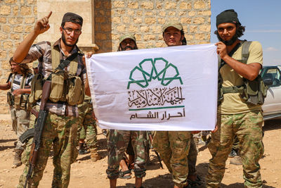 Portrait o soldiers holding banner standing outdoors