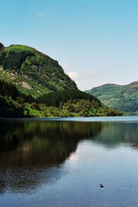 Scenic view of lake by mountains against clear sky