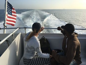 Man and woman sitting on boat in sea against sky