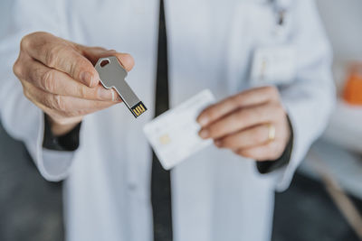 Male doctor holding usb stick while standing at clinic