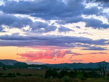 Scenic view of dramatic sky over land during sunset