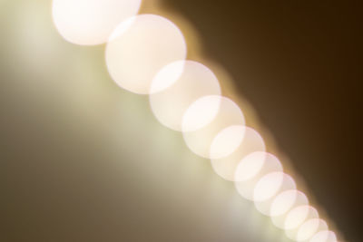 Defocused image of illuminated lights against sky at night