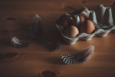 High angle view of eggs with feathers on wooden table