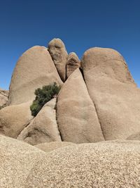 Low angle view of rock formations against clear blue sky