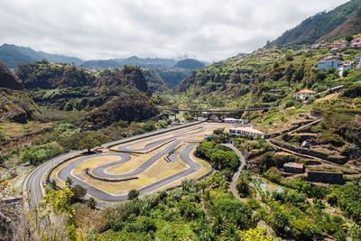 High angle view of winding road by mountains against cloudy sky