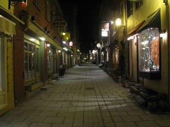 Illuminated walkway amidst buildings at night
