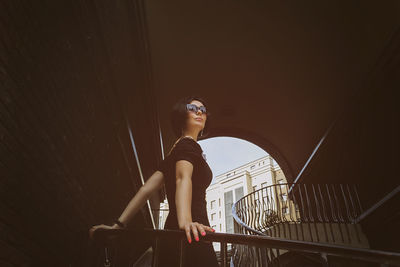 A pretty charming middle-aged woman in a black dress and sunglasses strolls through the stairs