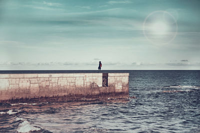 Woman standing on beach against sky