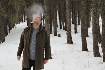 Man standing on snow covered field and smoking