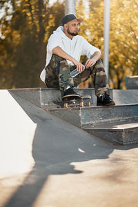 Full length of man with skateboard sitting on steps