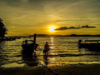 Silhouette people on boat at beach during sunset