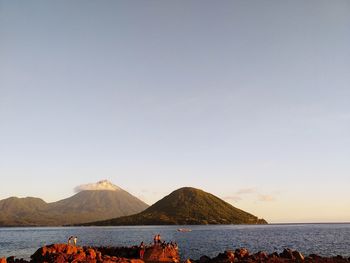 Scenic view of sea and mountains against clear sky