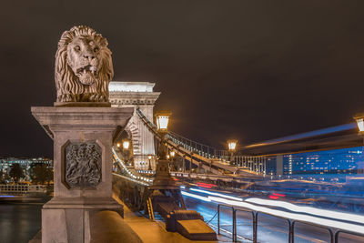 Lion's head on the chain bridge at night. light trails.