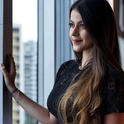 Portrait of smiling woman standing against window