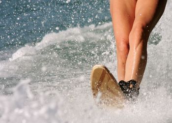 Low section of woman surfing in sea