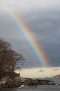 Scenic view of rainbow over sea against sky