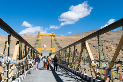 Rear view of people walking on bridge in city