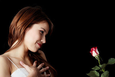 Portrait of a smiling young woman over black background