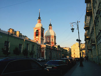 Cars on street amidst buildings in city against sky