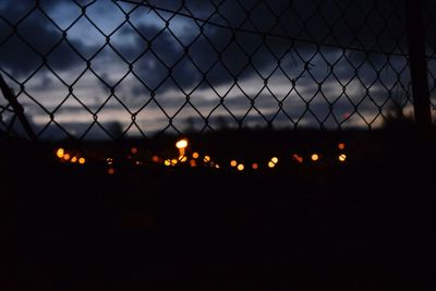 Close-up of illuminated chainlink fence against sky