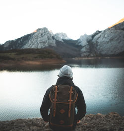 Rear view of man looking at lake against mountain