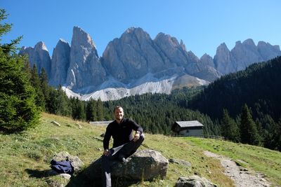 Man sitting on rock against mountains