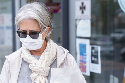 Woman wearing mask and sunglasses standing outdoors