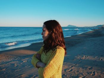 Woman standing on beach against clear sky