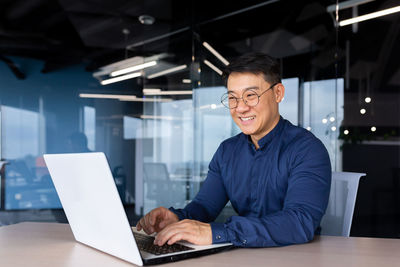 Portrait of young man using laptop at office