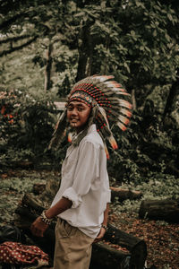 Portrait of smiling man wearing headdress in forest