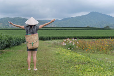 Rear view of woman standing on field against sky