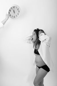 Pregnant woman standing by clock
