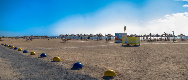 Panoramic view of people on beach against blue sky