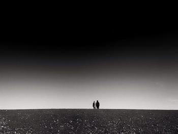 Silhouette people standing on landscape against clear sky