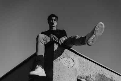 Low angle view of young man looking away against wall