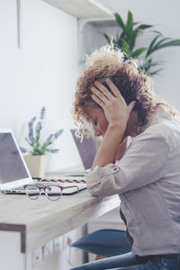 Side view of young woman using mobile phone while sitting at home