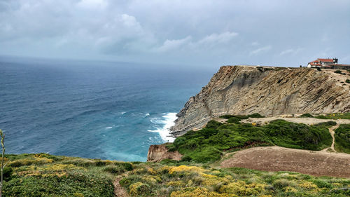 Scenic view of cliff by sea against sky